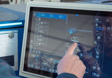 eine Hand bedient einen Touchscreen von einer Machine für die Metallbearbeitung